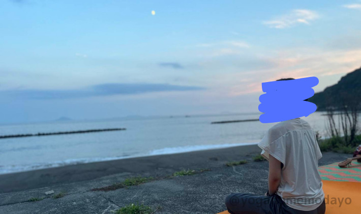 夕方月が出始めた海辺でヨガをする写真